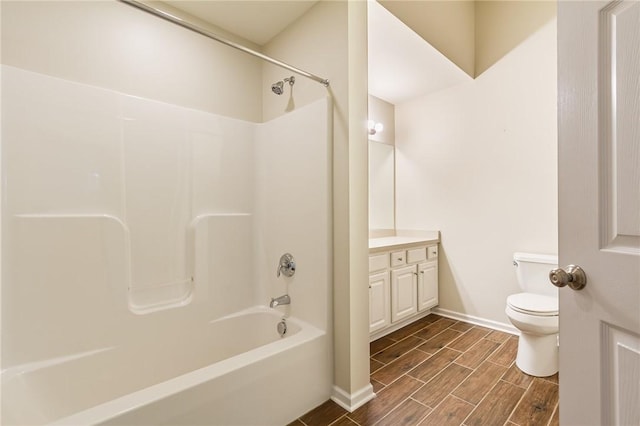 bathroom featuring bathing tub / shower combination, toilet, wood tiled floor, vanity, and baseboards