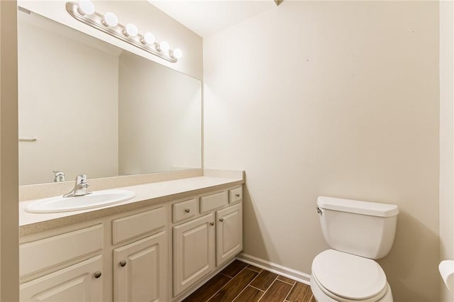 bathroom featuring wood finish floors, vanity, toilet, and baseboards