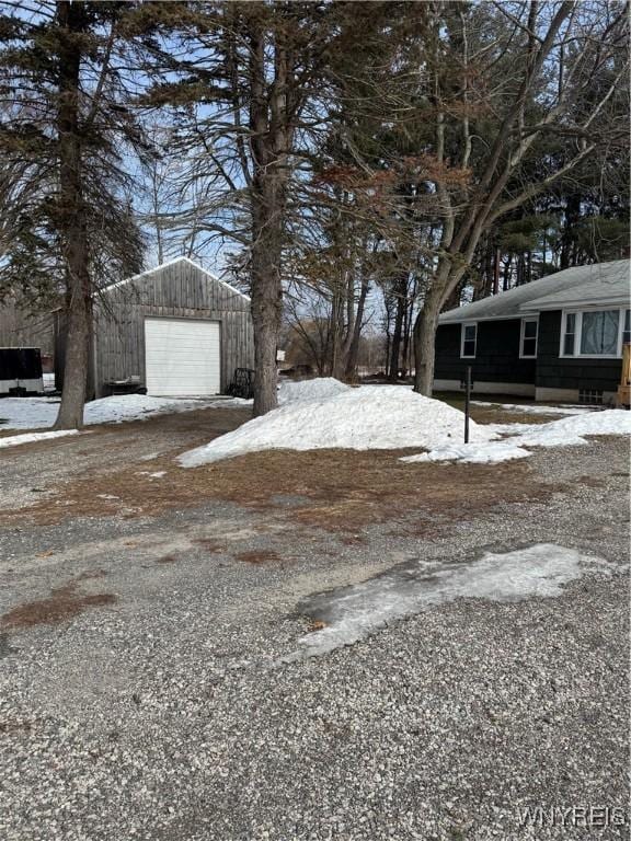 yard layered in snow featuring a garage and an outdoor structure