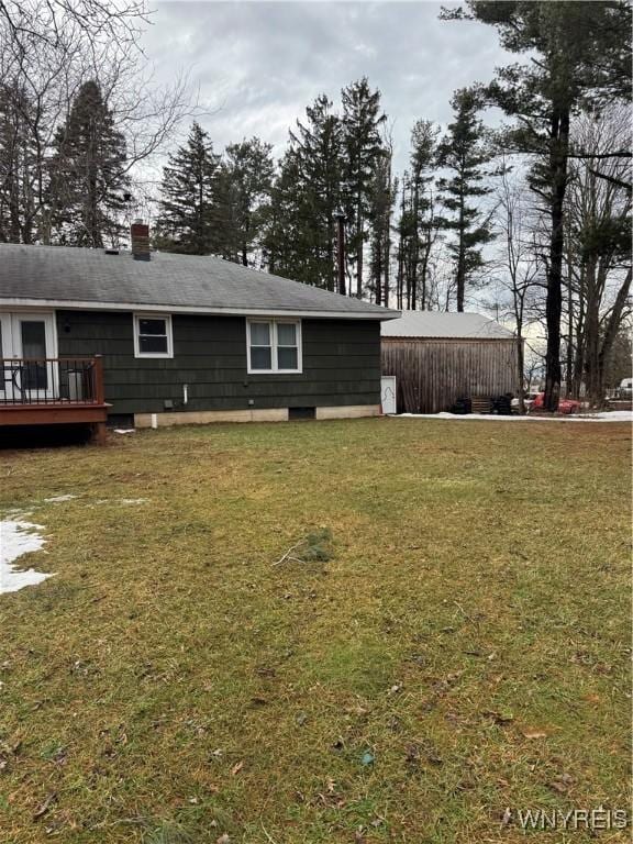 rear view of property featuring a deck, a lawn, and a chimney