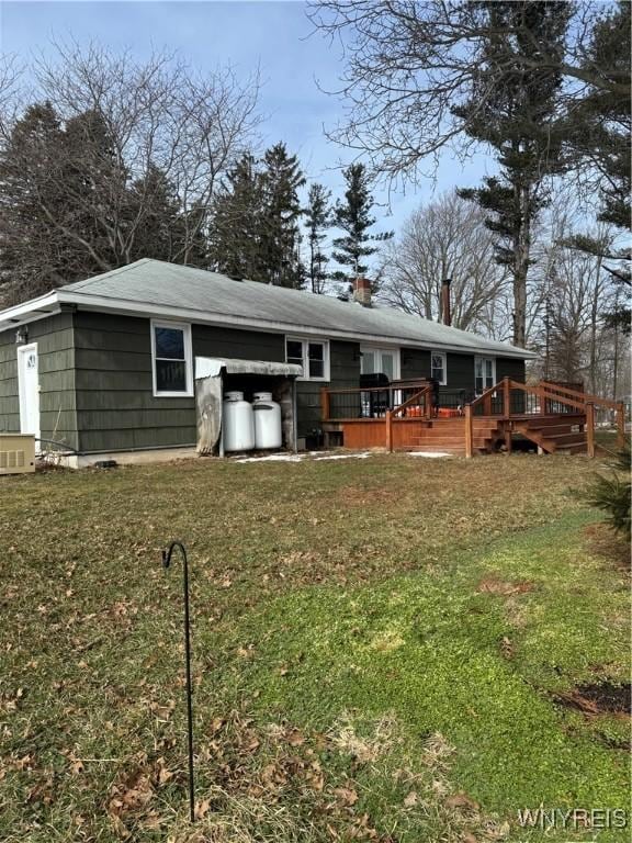 back of property featuring a chimney, a yard, and a deck