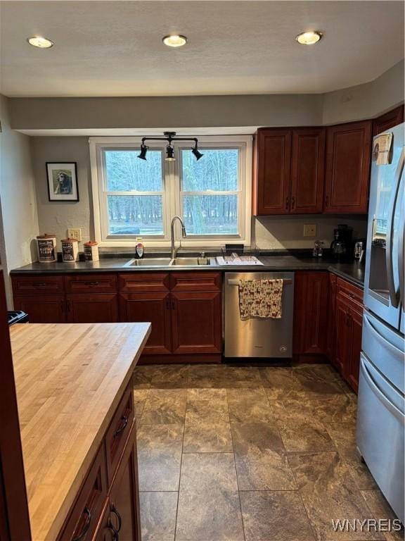 kitchen with a healthy amount of sunlight, butcher block countertops, appliances with stainless steel finishes, and a sink