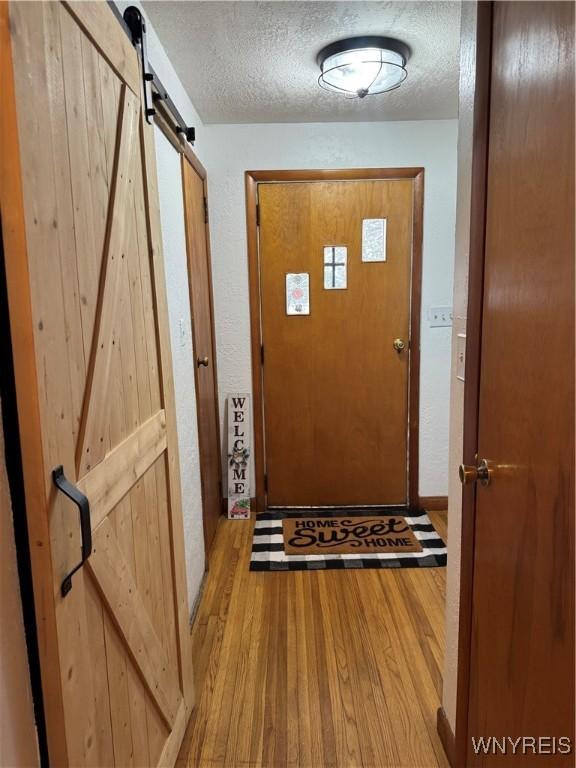 doorway featuring a barn door, a textured ceiling, and wood finished floors