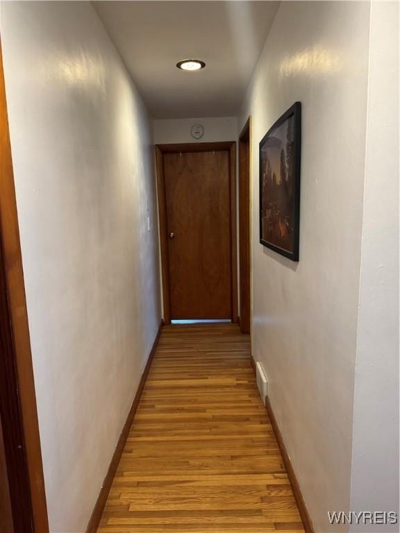 hall with light wood-type flooring, visible vents, and baseboards