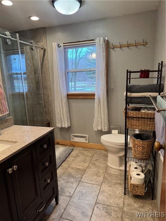 bathroom with visible vents, toilet, a stall shower, vanity, and baseboards