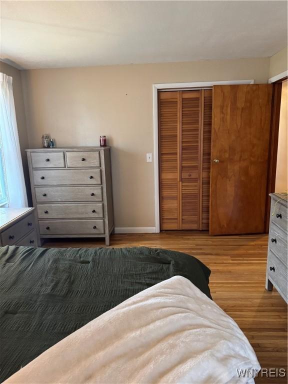 bedroom with a closet, wood finished floors, and baseboards