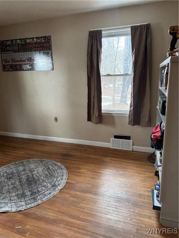 unfurnished room with wood finished floors, visible vents, and baseboards