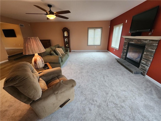 living area with a fireplace, carpet flooring, visible vents, and baseboards