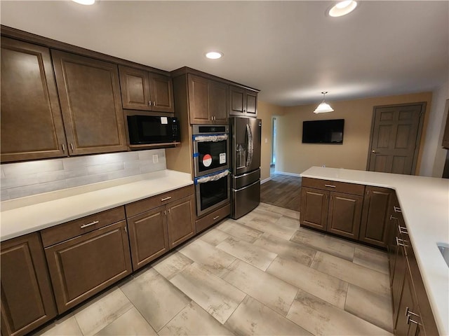 kitchen with black microwave, light countertops, fridge with ice dispenser, and stainless steel double oven