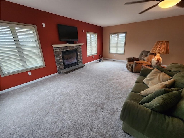 carpeted living area with a ceiling fan, a fireplace, and baseboards