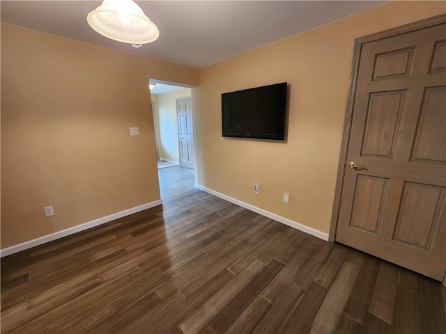 spare room with baseboards and dark wood-style flooring