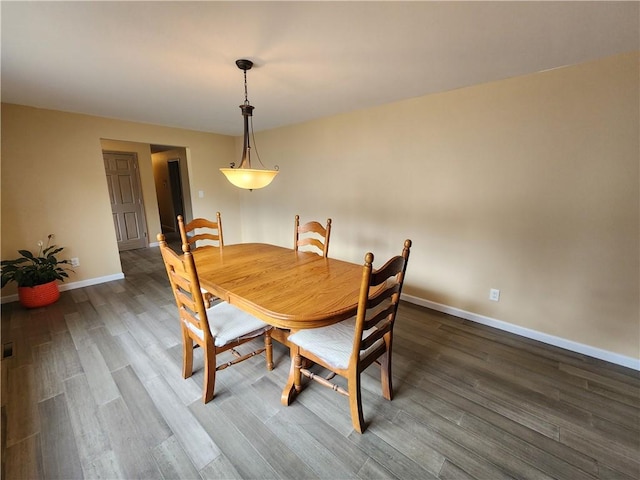 dining space with baseboards and wood finished floors