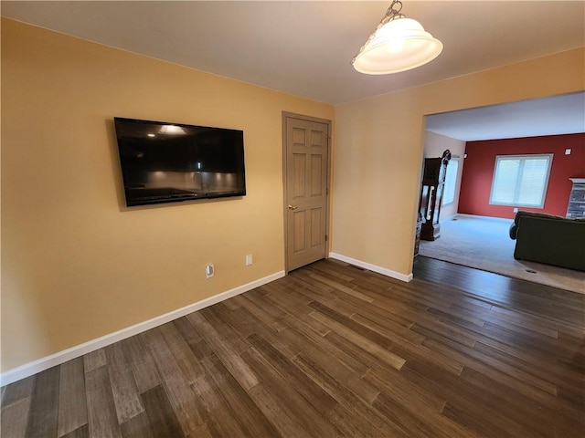 unfurnished room featuring dark wood-type flooring and baseboards