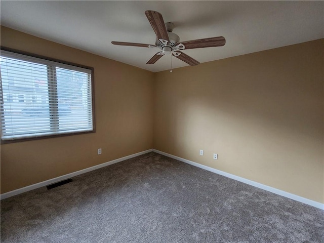 empty room with carpet floors, visible vents, baseboards, and ceiling fan