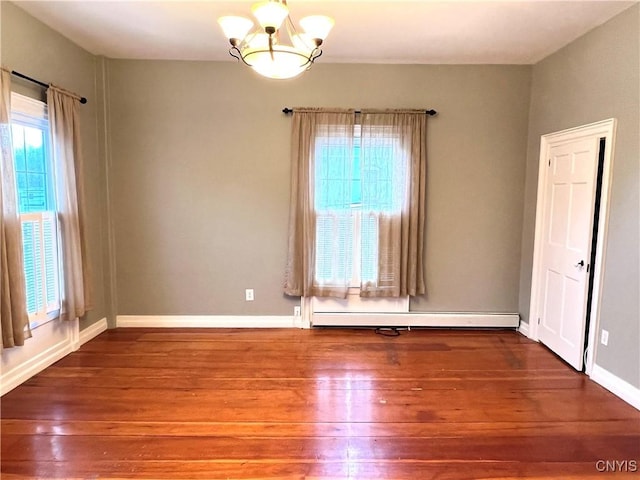 spare room with an inviting chandelier, baseboards, a baseboard heating unit, and wood finished floors