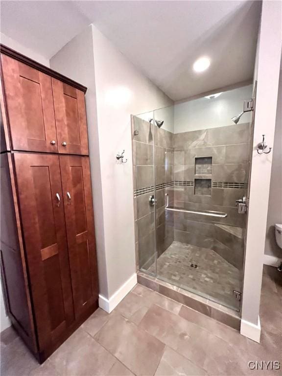 bathroom with a shower stall and baseboards