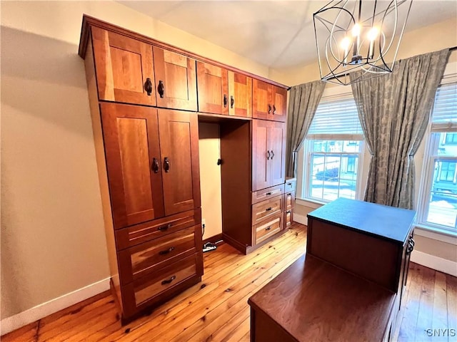 interior space featuring light wood finished floors, multiple windows, baseboards, and a chandelier