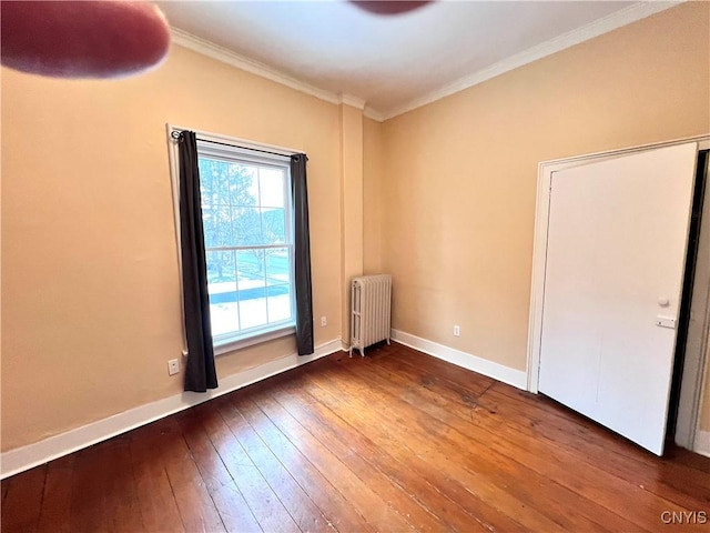 unfurnished room featuring crown molding, hardwood / wood-style floors, baseboards, and radiator