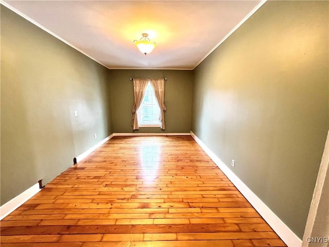 unfurnished room featuring hardwood / wood-style flooring, baseboards, and ornamental molding