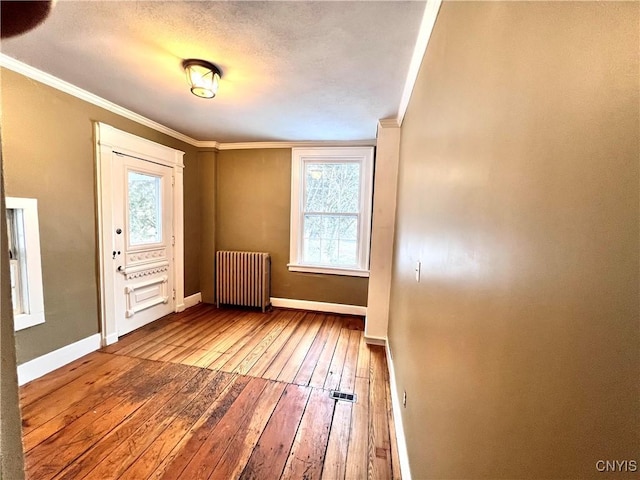 foyer featuring radiator, baseboards, crown molding, and hardwood / wood-style floors