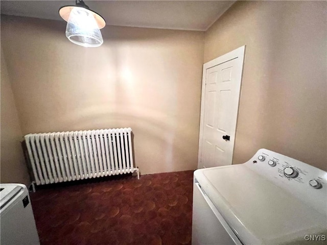 clothes washing area with laundry area, radiator heating unit, dark carpet, and washer / dryer