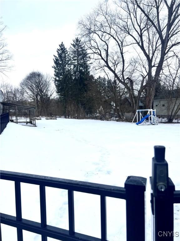 snowy yard featuring a playground