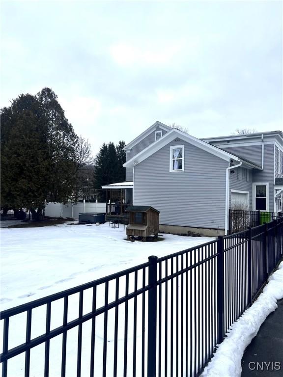 snow covered property with a fenced backyard and a deck