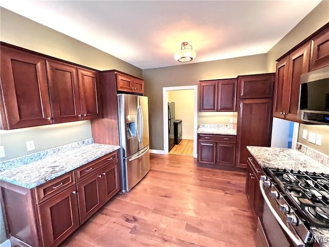 kitchen featuring light wood-type flooring, light stone countertops, baseboards, and stainless steel appliances