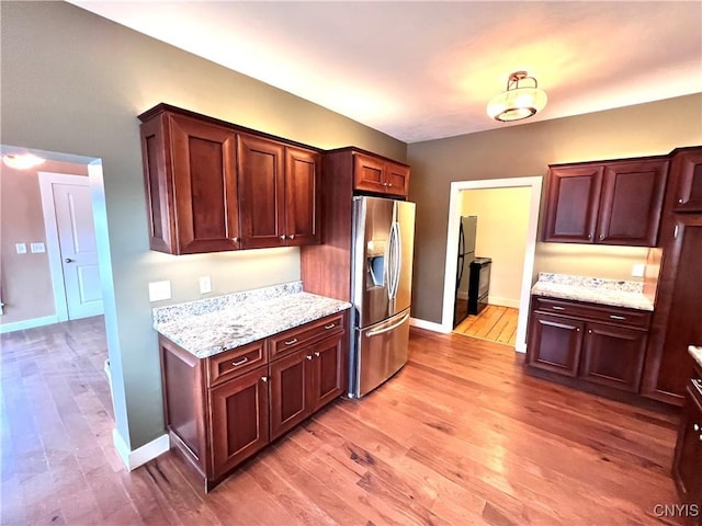 kitchen with light wood finished floors, baseboards, and stainless steel fridge with ice dispenser