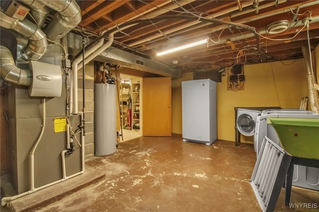 unfinished below grade area with visible vents, water heater, independent washer and dryer, freestanding refrigerator, and heating unit