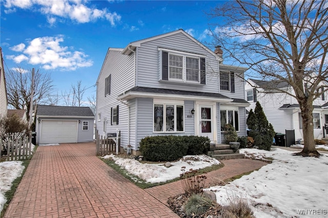 view of front of home with a garage, a chimney, fence, decorative driveway, and an outdoor structure