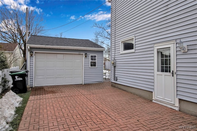 detached garage with decorative driveway and fence