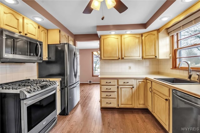 kitchen featuring light brown cabinets, stainless steel appliances, wood finished floors, a sink, and light countertops