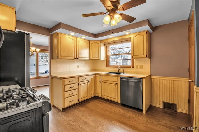 kitchen featuring stainless steel appliances, light countertops, visible vents, wainscoting, and a sink