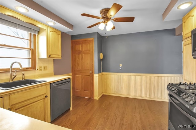 kitchen with wood finished floors, a sink, range with gas stovetop, wainscoting, and dishwasher