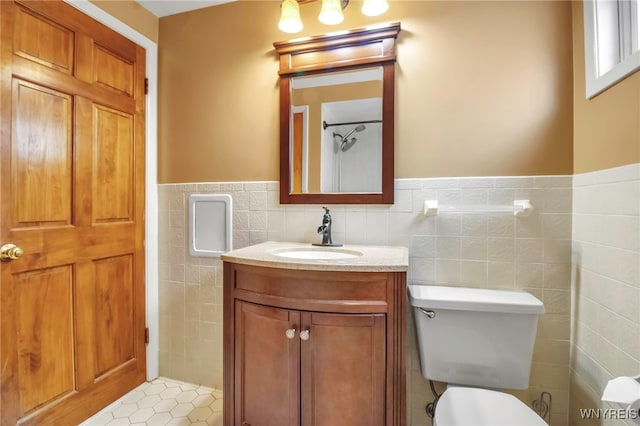 bathroom with toilet, wainscoting, vanity, and tile walls