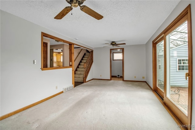 spare room featuring light carpet, stairway, plenty of natural light, and visible vents