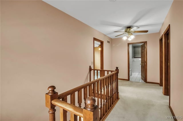 corridor with light carpet, visible vents, an upstairs landing, and baseboards