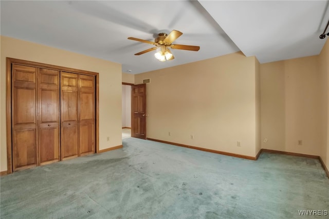 unfurnished bedroom with baseboards, a closet, a ceiling fan, and light colored carpet