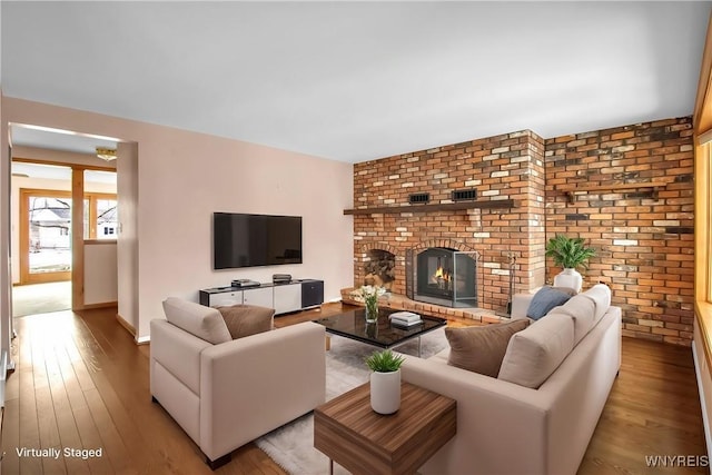 living area with a brick fireplace and wood finished floors