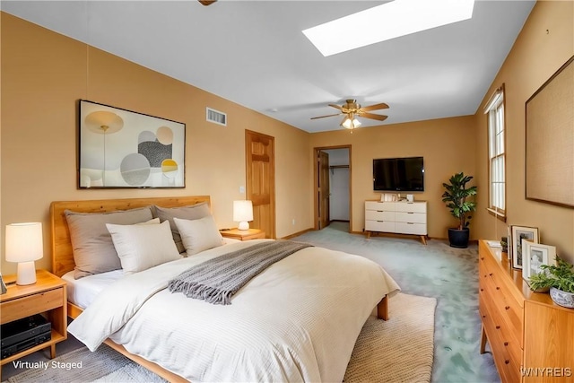 carpeted bedroom featuring a skylight, ceiling fan, and visible vents