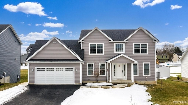 colonial inspired home featuring aphalt driveway and an attached garage