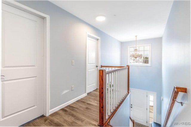 12 Kevwood Ln, Lancaster, NY 14086 - corridor featuring baseboards, wood finished floors, a notable chandelier, and an upstairs landing