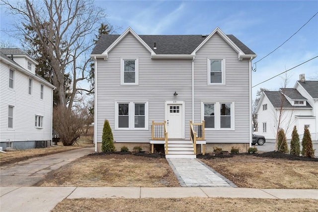 traditional-style home featuring central AC unit and roof with shingles