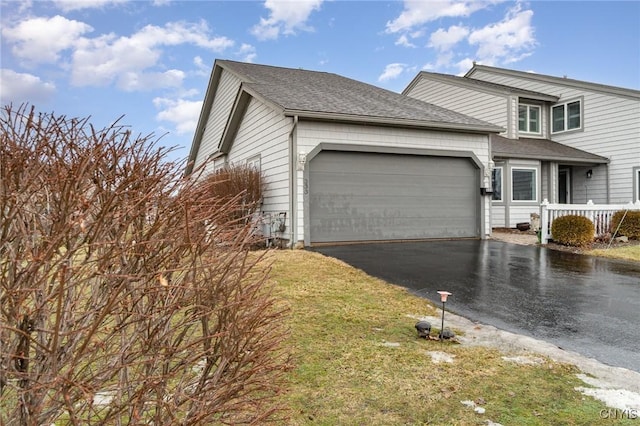 view of front of property featuring an attached garage, aphalt driveway, and roof with shingles