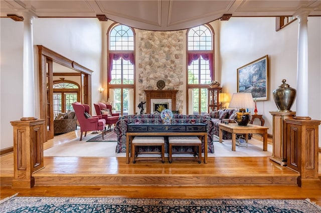 sitting room with a healthy amount of sunlight, a fireplace, decorative columns, and a towering ceiling