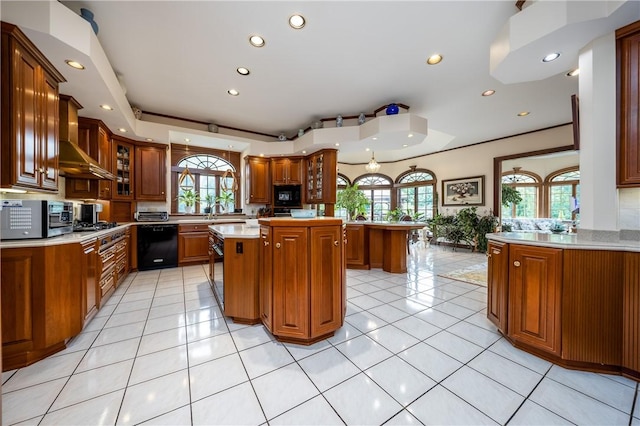 kitchen with brown cabinets, black appliances, light countertops, and wall chimney range hood