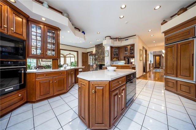 kitchen featuring brown cabinetry, light tile patterned flooring, light countertops, black appliances, and recessed lighting