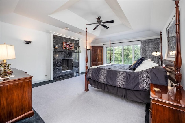 bedroom featuring carpet floors, a raised ceiling, a premium fireplace, ceiling fan, and baseboards