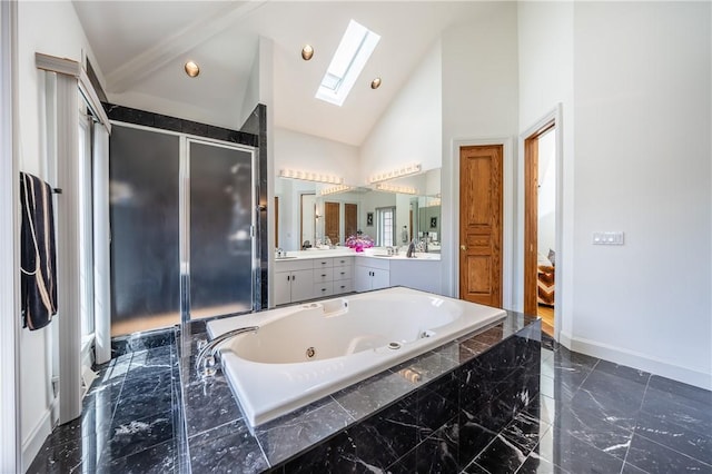 bathroom with a skylight, marble finish floor, a stall shower, vanity, and a tub with jets